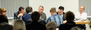 Mitglieder des Forum Silberhöhe sitzen an einem langen Tisch vor dem Audiotorium während einer Sitzung.